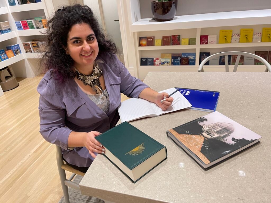 Tara Sitting smiling while at a desk with books