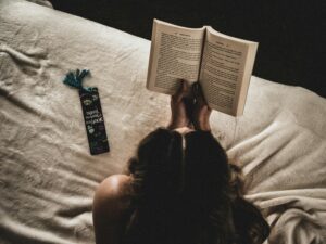 Woman reading a book in bed with a vintage bookmark, capturing a cozy and peaceful evening moment at home.